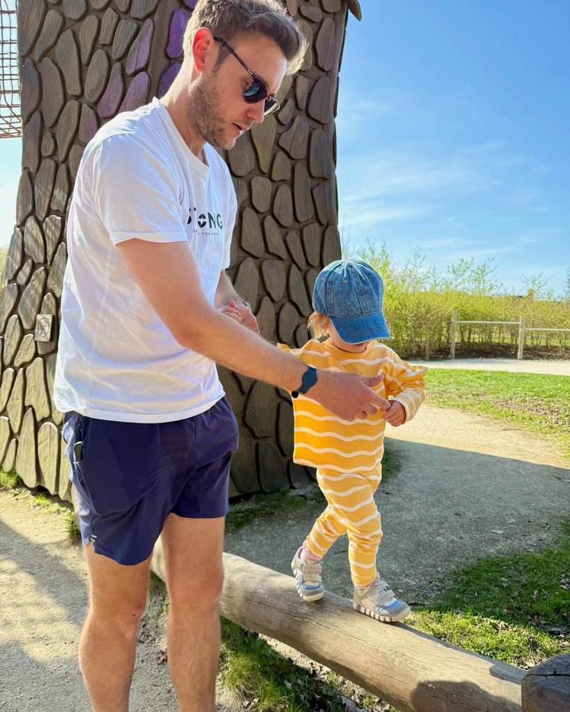Staurt helping annabella walk along a log