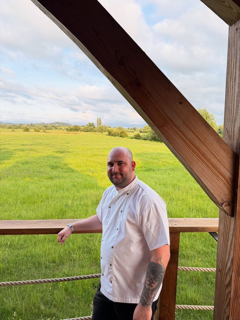man in chef's whites in front of a green field 