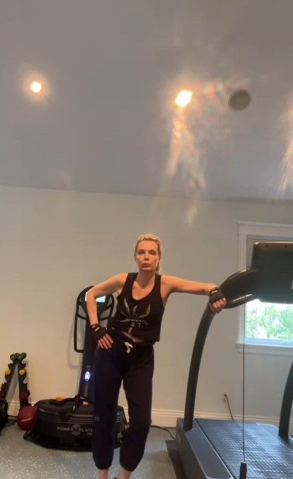photo of michelle pfeiffer standing beside treadmill in home gym