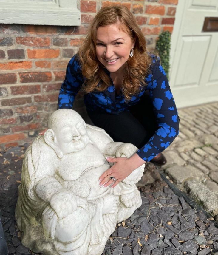 Irita Marriott crouching next to a Buddha statue