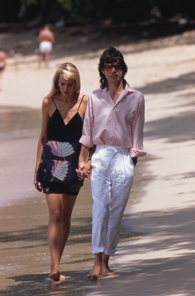 Passeando pela praia, de mãos dadas com Mick Jagger em Mustique, 1987.