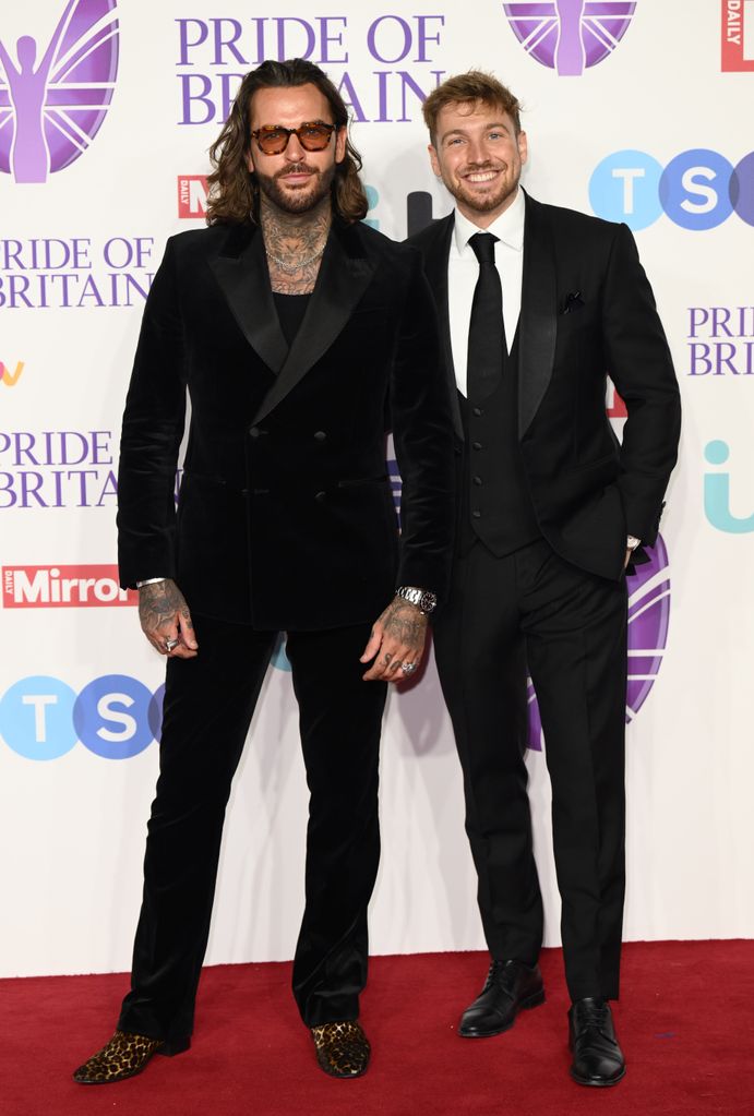two men on red carpet wearing suits 