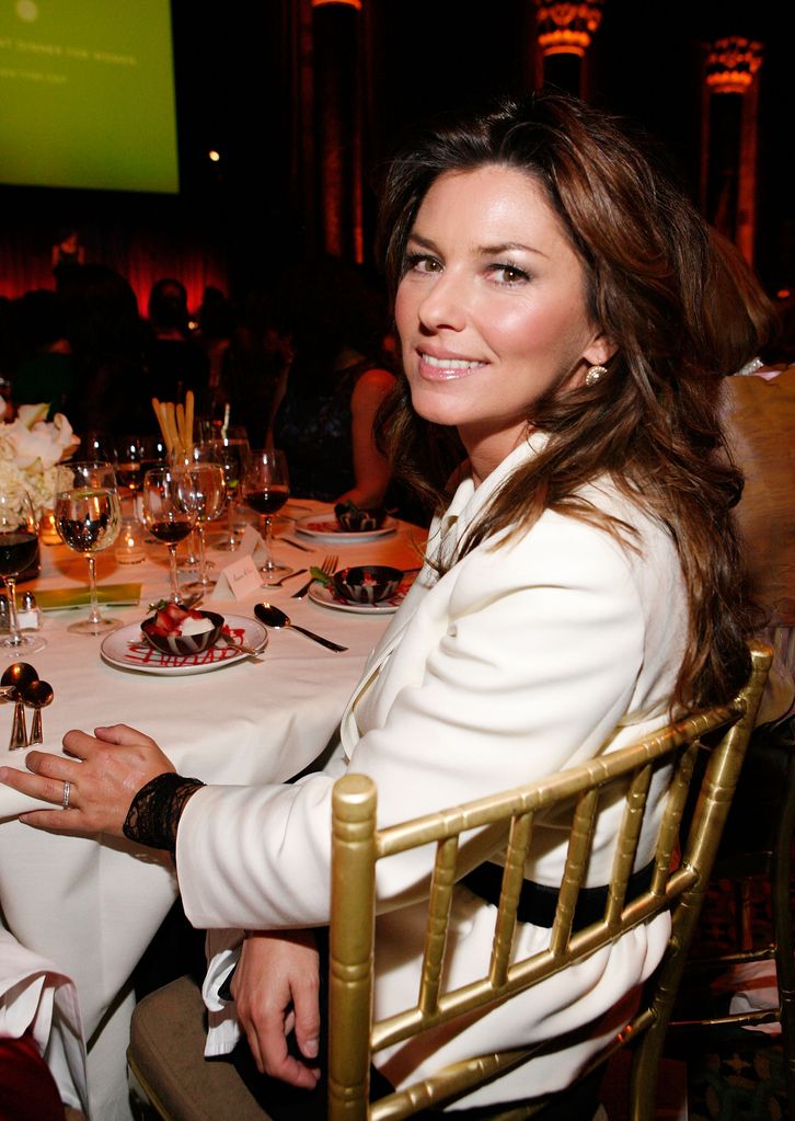 Shania Twain sitting at a dinner table with wine and dessert