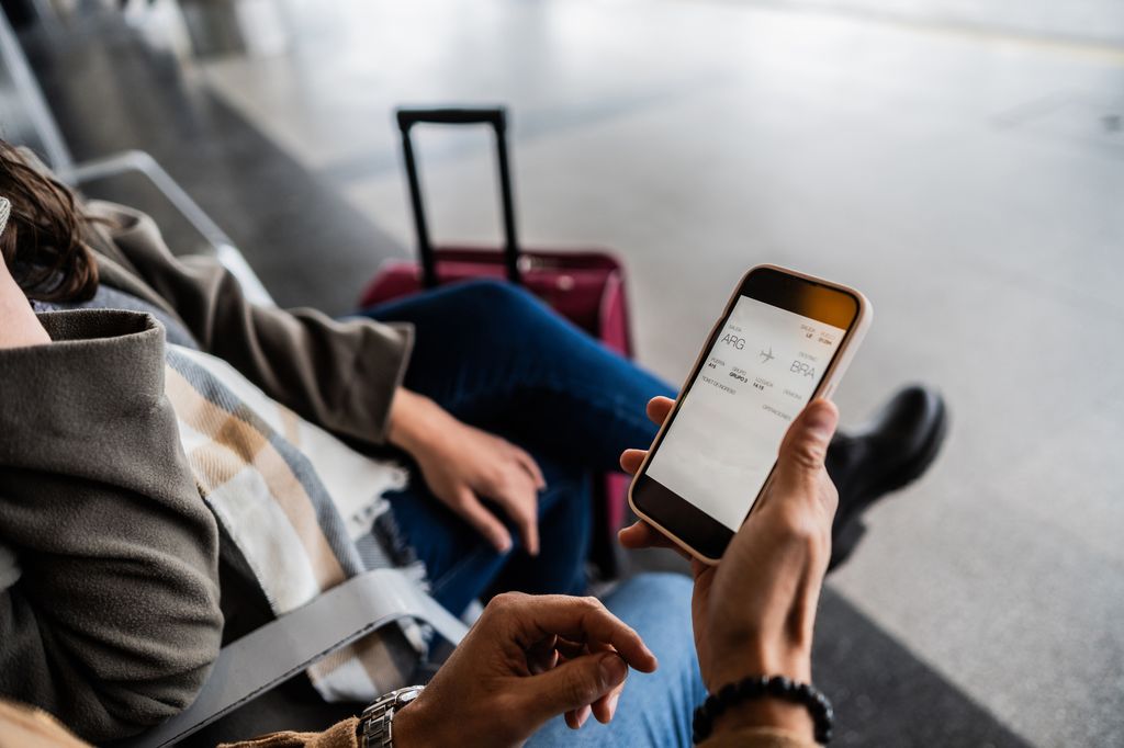 Close-up of hands using mobile phone view airplane ticket on airport