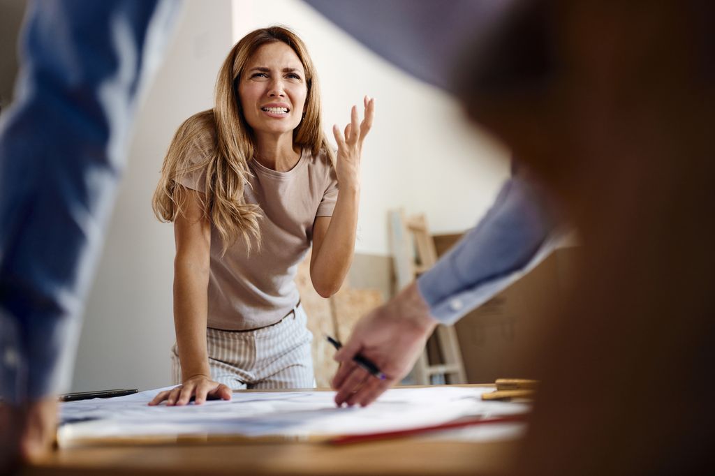 Displeased woman arguing with a building contractor while having problems with plans in the apartment.
