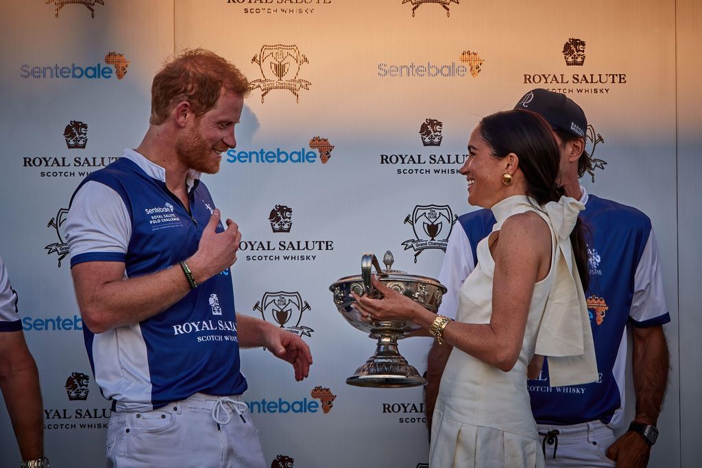 Meghan was all smile as she gave Harry and his team the trophy