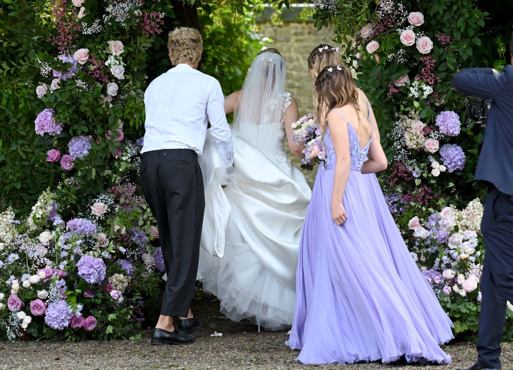 Anne-Marie Corbett walking into her wedding with her two daughters in lilac bridesmaid dresses