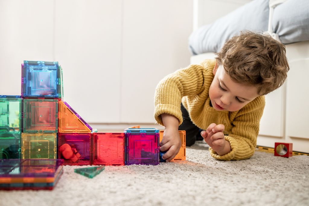 boy playing with magnet tiles in bedroom