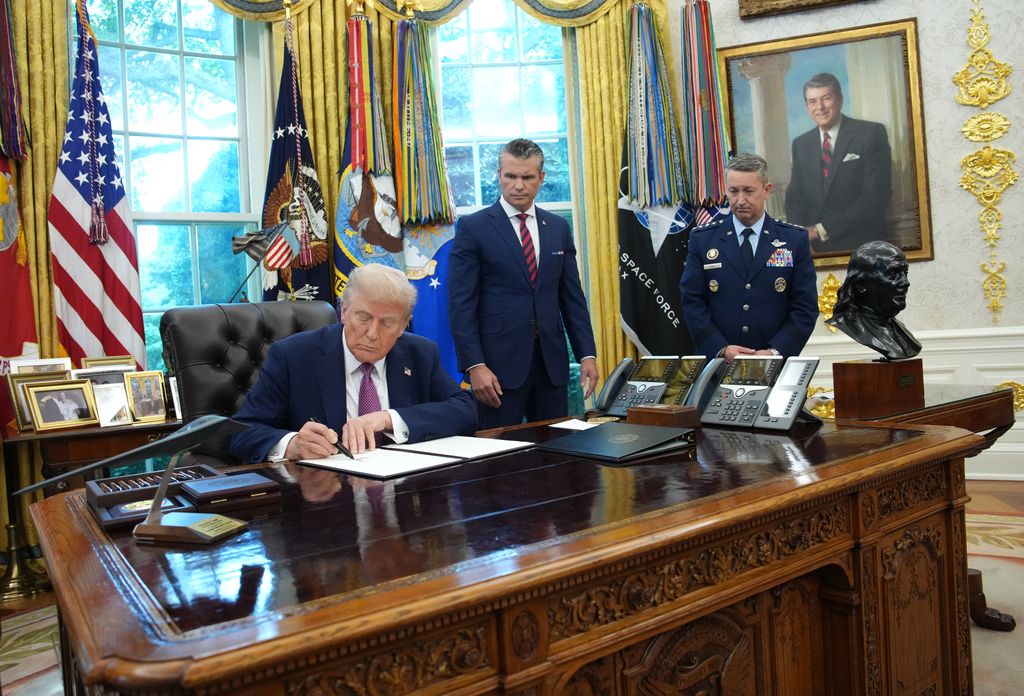 President Donald Trump signs an executive order renaming the Department of Defense as the Department of War as U.S. Defense Secretary Pete Hegseth (C) and Chairman of the Joint Chiefs of Staff Air Force Gen. Dan Caine (R) watch