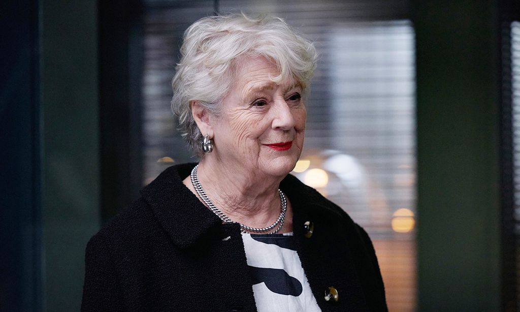 Femme aux cheveux blancs et aux vêtements sombres souriant