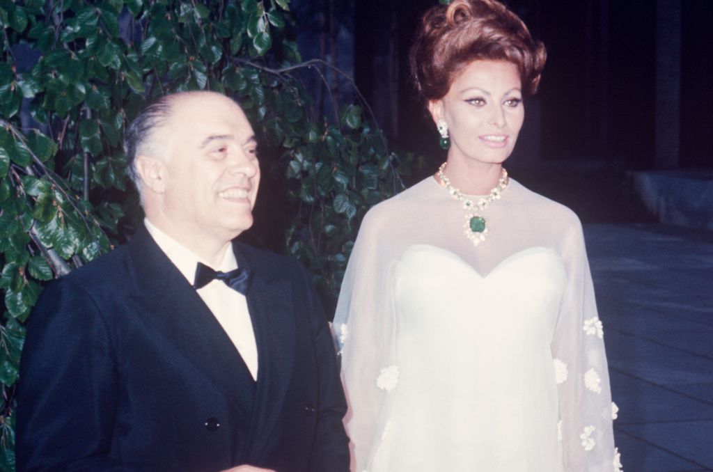 Sophia Loren wearing a white dress with her hair up next to her husband Carol Ponti