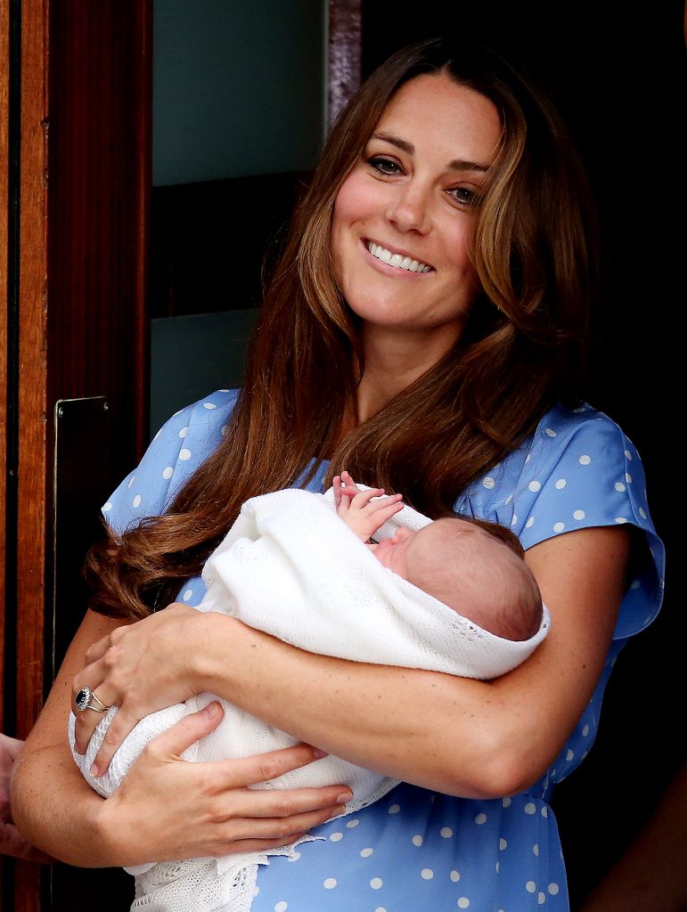 Princess Kate smiling whilst holding new-born Prince George at the Lindo Wing in 2013