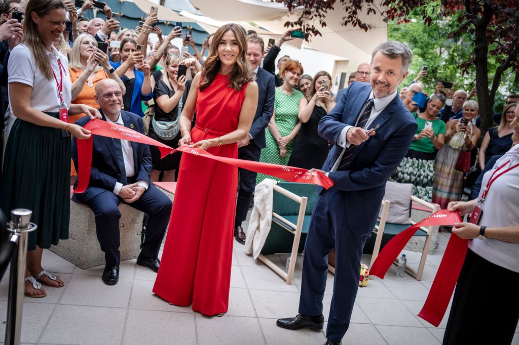 Queen Mary cutting the ribbon in red jumpsuit