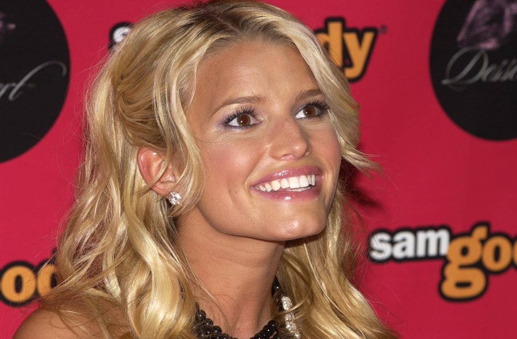 5 magasins autrefois appréciés du 20e siècle et disparus à jamais 5 Jessica Simpson sourit à la caméra dans une photo inclinée, avec le logo Sam Goody imprimé en rose vif derrière elle.