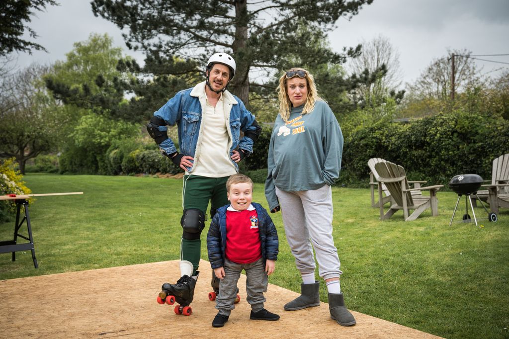 A man a wearing rollerblades standing next to a woman and child in garden