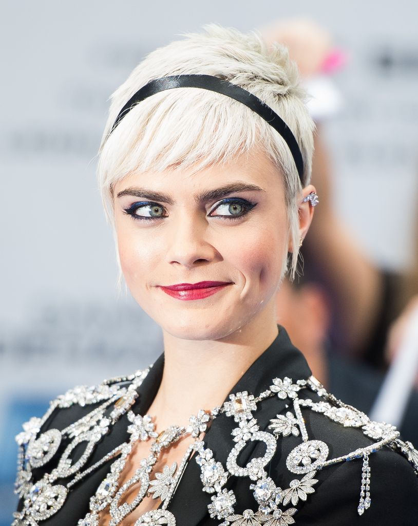 Cara Delevingne with short blonde hair and black jewelled blazer