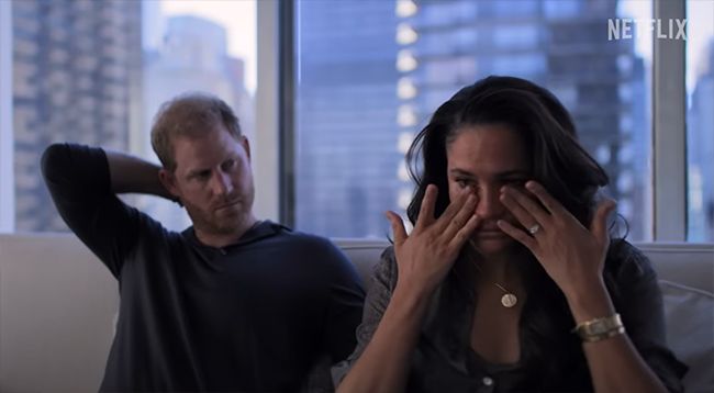 Meghan Markle wipes her tears and Prince Harry looks tense whilst looking at her in a still from their Netflix show