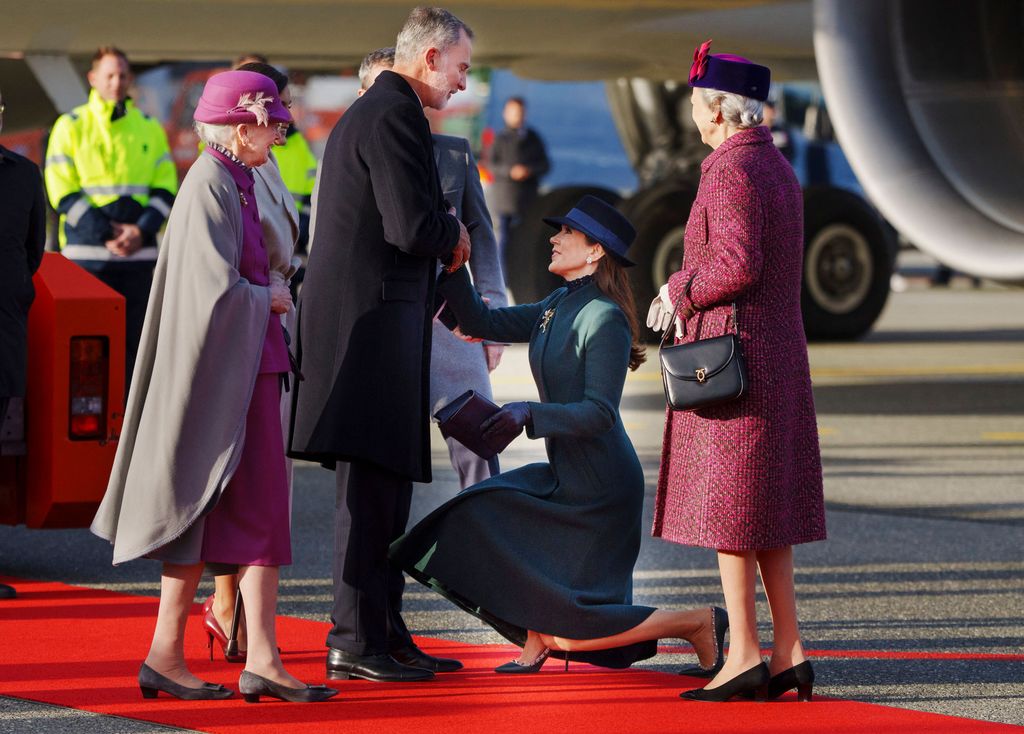 Queen Margrethe II of Denmark looks on as Crown Princess Mary of Denmark curtsies to King Felipe of Spain