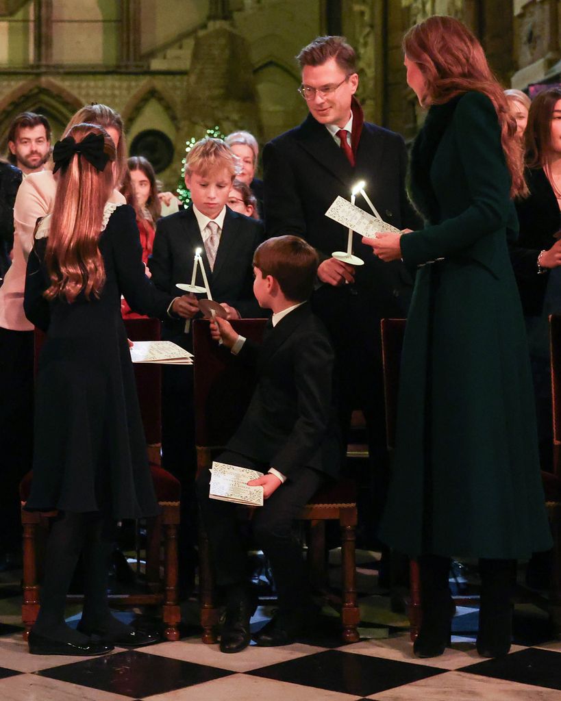 Prince Louis lighting a candle while with Princess Charlotte and Kate Middleton