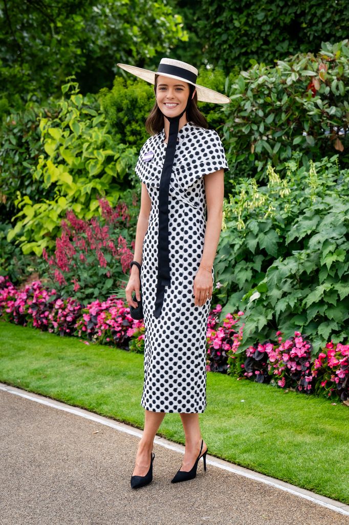 Tegan Dalman woman wears a white and black polka-dot midi dress with a matching straw hat and necktie detail at Royal Ascot. (wearing a Karen Millen dress and hat and Mango shoes)