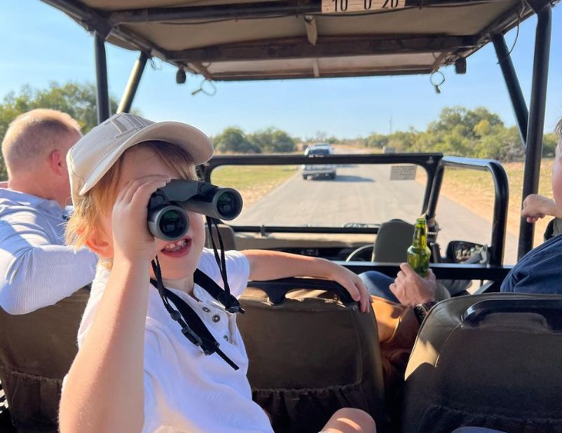 A young boy in a jeep using a pair of binoculars