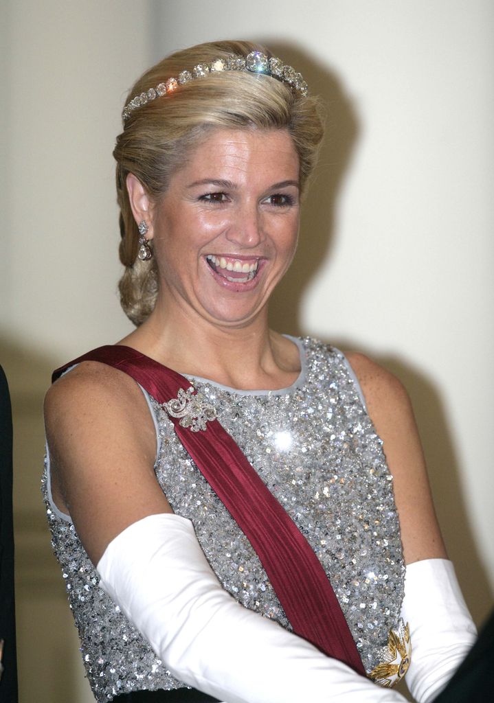 younger Queen Maxima laughing in silver dress and tiara