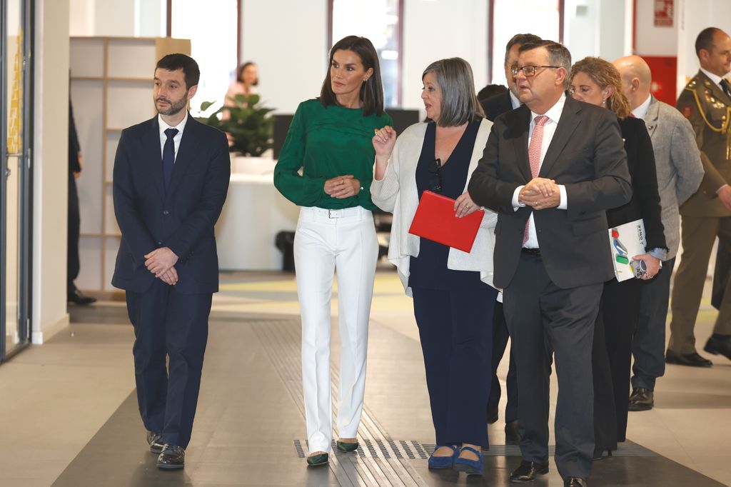 Queen Letizia talking to people in white trousers and green top