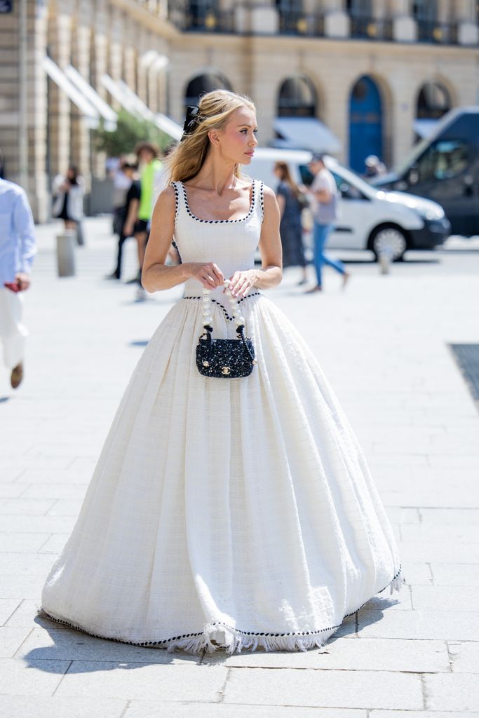 Tatiana Korsakova wears white wide dress, black bag outside Chanel during the Haute Couture Fall/Winter 2024/2025 as part of  Paris Fashion Week