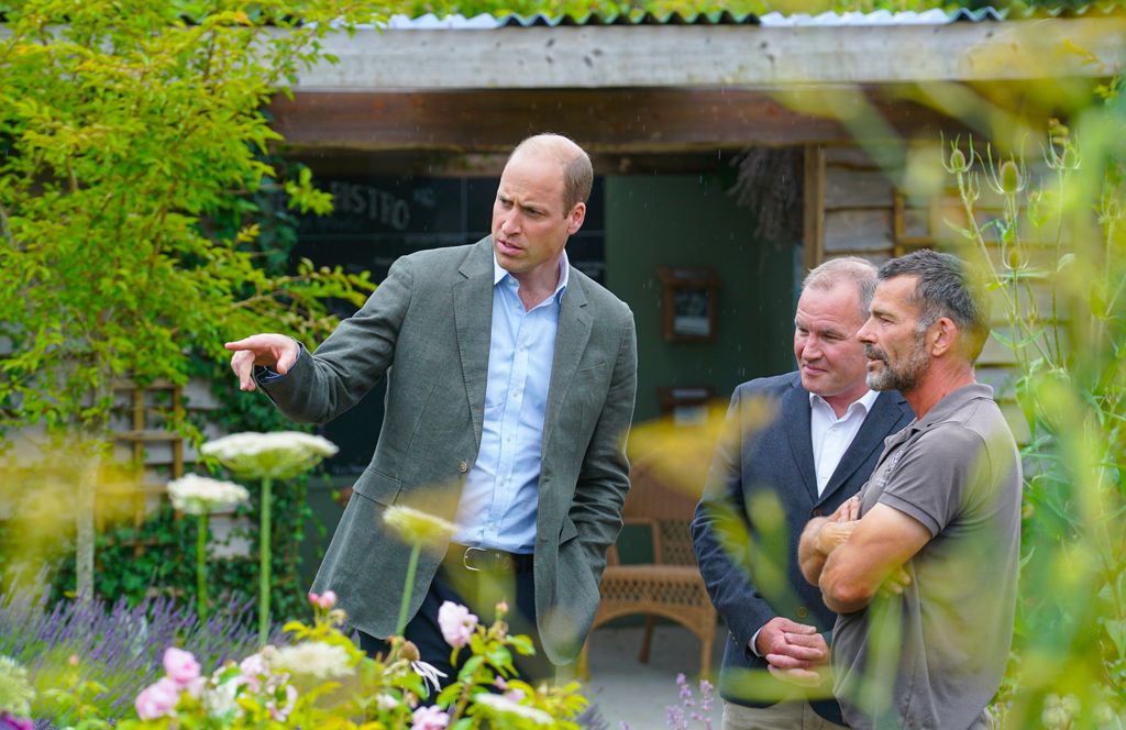 Prince William in a garden with two men