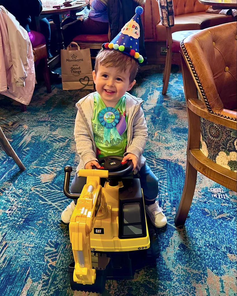 young boy sitting on yellow digger toy 