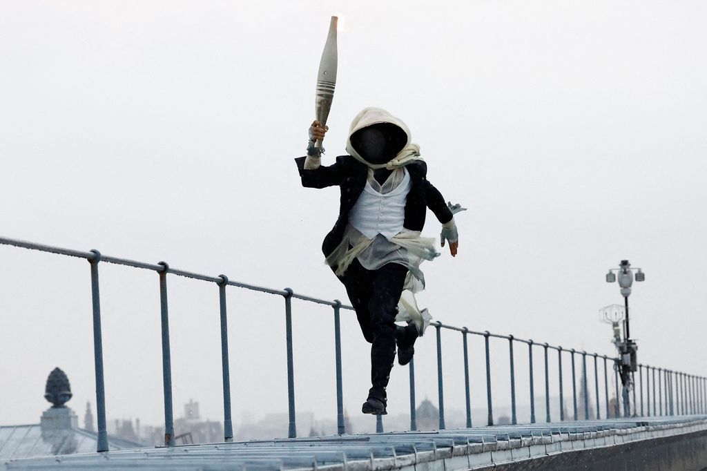 A torchbearer runs atop the Musee d'Orsay during the opening ceremony