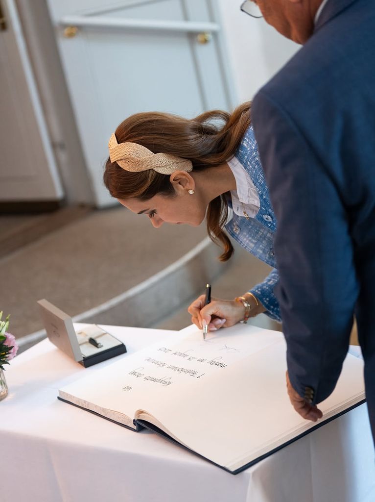 Queen Mary of Denmark signing a giant book looking a lot like Kate Middleton 