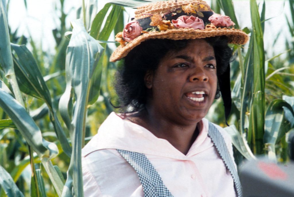 Oprah Winfrey with a hat on walking through the corn fields in a scene from the film 'The Color Purple', 1985. (Photo by Warner Brothers/Getty Images)