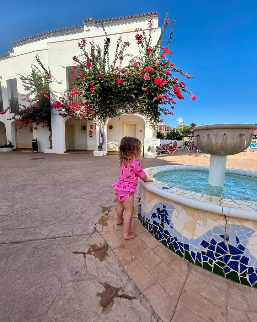 young girl standing by water fountain