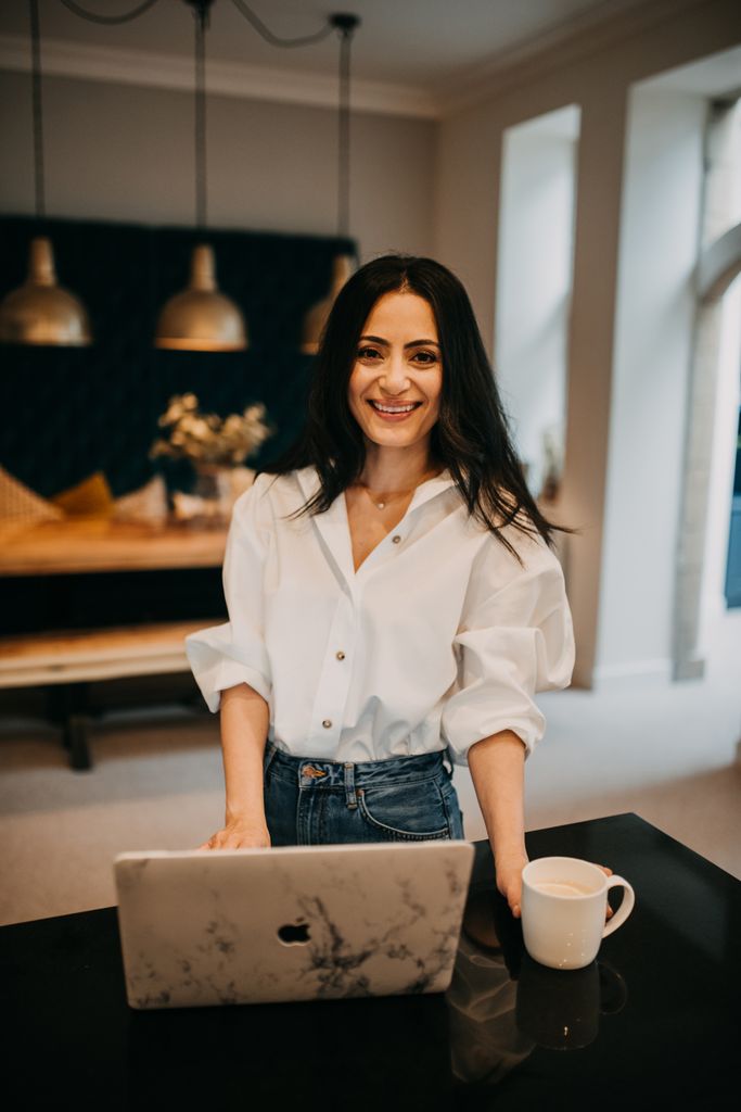 woman in a white shirt and jeans with a coffee and laptop