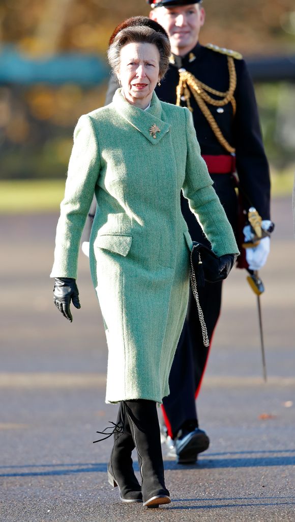 Princesa Anne andando com um casaco verde e botas com franjas