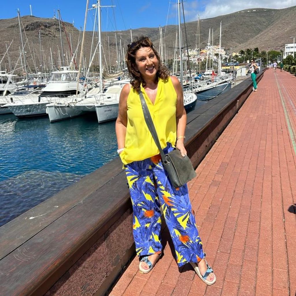 jane mcdonald posing on jetty in yellow outfit 