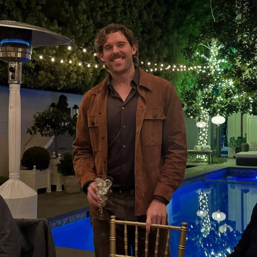 Christopher Schwarzenegger posing in front of swimming pool in brown outfit