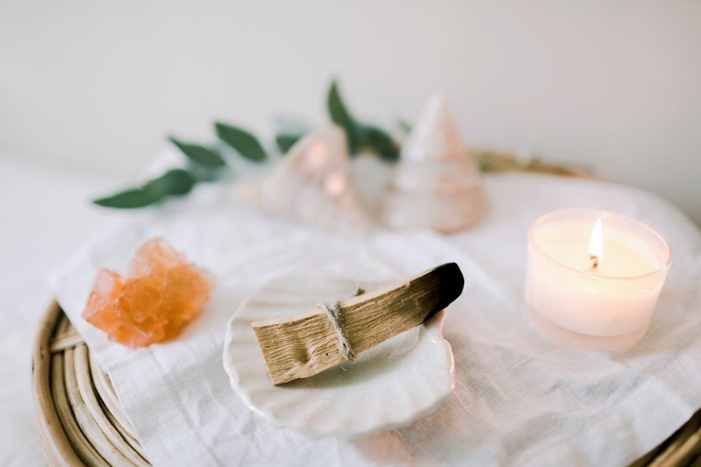 A wooden tray with ceramic plate on a linen cloth, eucalyptus leaves, candle, sea shells  and Palo Santo ready to burn. Ritual objects for spiritual practice. Ceremony with Palo Santo. Mental health.