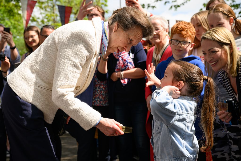 Princess Anne presents a young girl with a commemorative tin of old coins as she visits a Coronation street party in Swindon