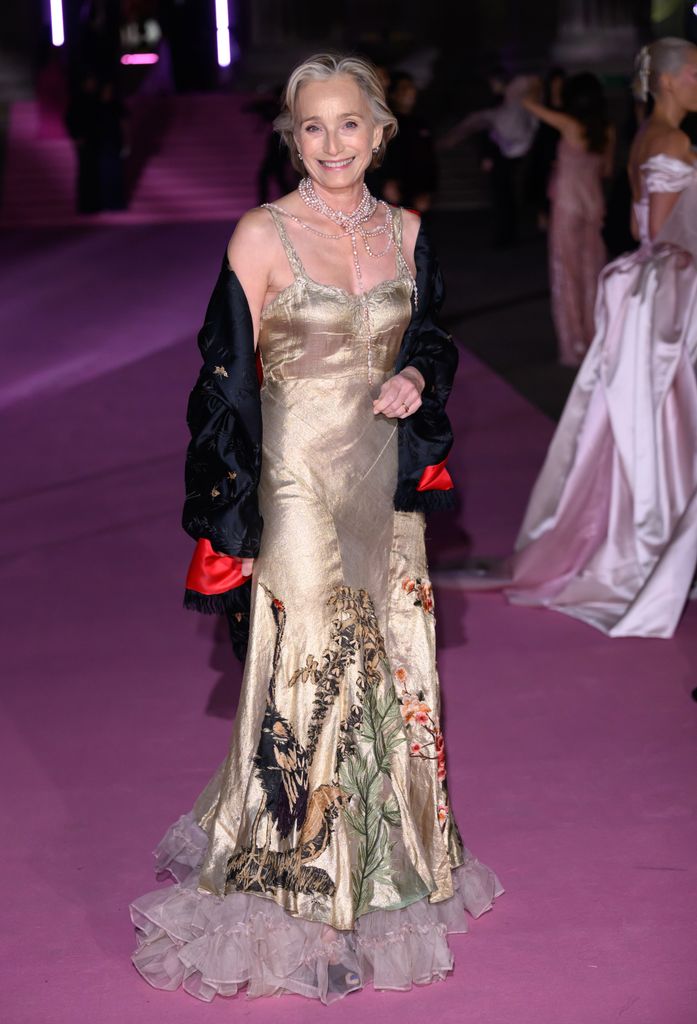 Dame Kristin Scott Thomas on pink carpet in gold gown