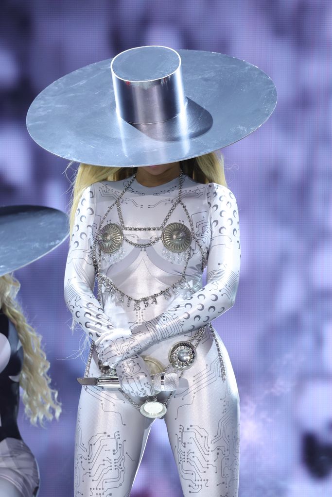 Beyonce in silver catsuit and hat looking down