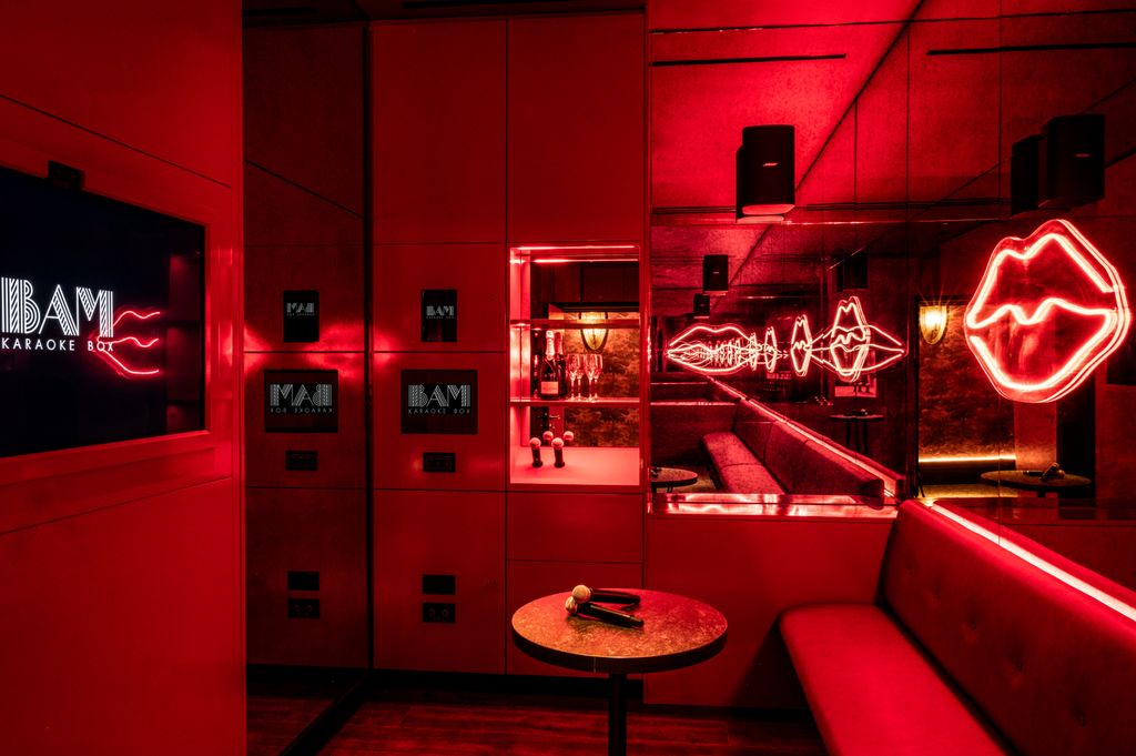 A private karaoke room with neon red lips and mirrors
