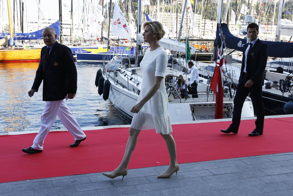 Princess Charlene in a white mini dress near boats