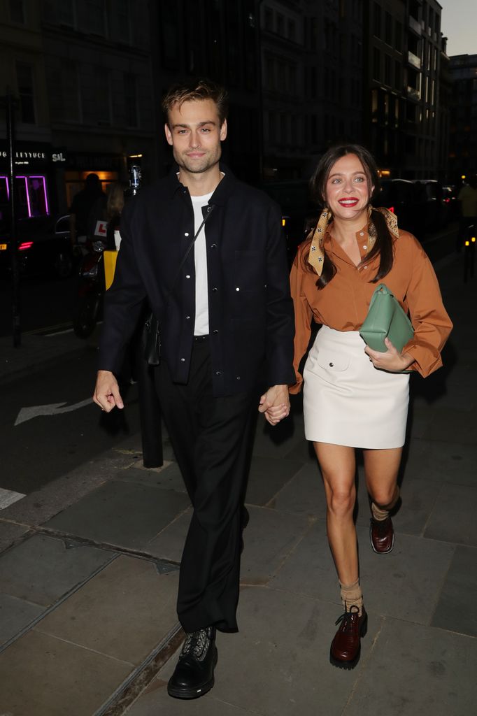 A brunette man and woman holding hands while walking in the street