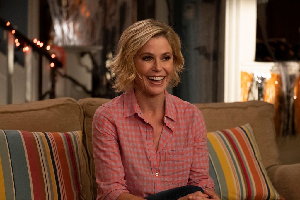 Julie Bowen sourit alors qu'elle est assise sur un canapé dans le rôle de Claire Dunphy dans Modern Family.