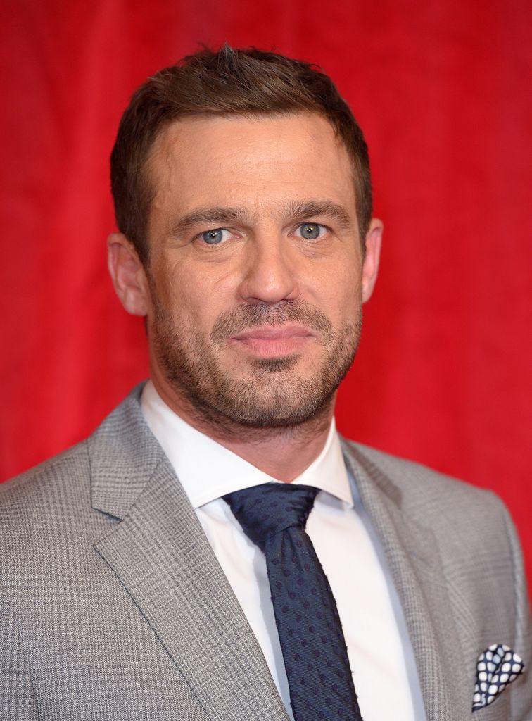Jamie Lomas in suit on red backdrop