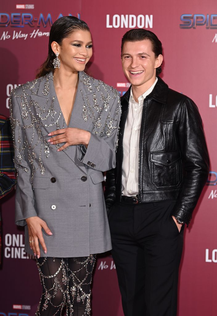 Tom Holland and Zendaya smiling on a red carpet