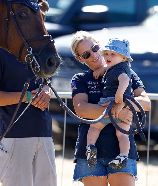 Zara Tindall holding son Lucas Tindall up to see a horse