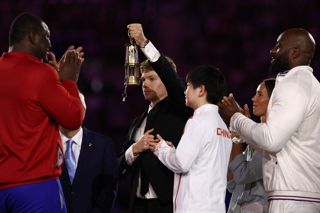 France's swimmer Leon Marchand arrives with the Olympic flame and shows it to athletes during the closing ceremony of the Paris 2024 Olympic Games at the Stade de France, in Saint-Denis, in the outskirts of Paris, on August 11, 2024. 